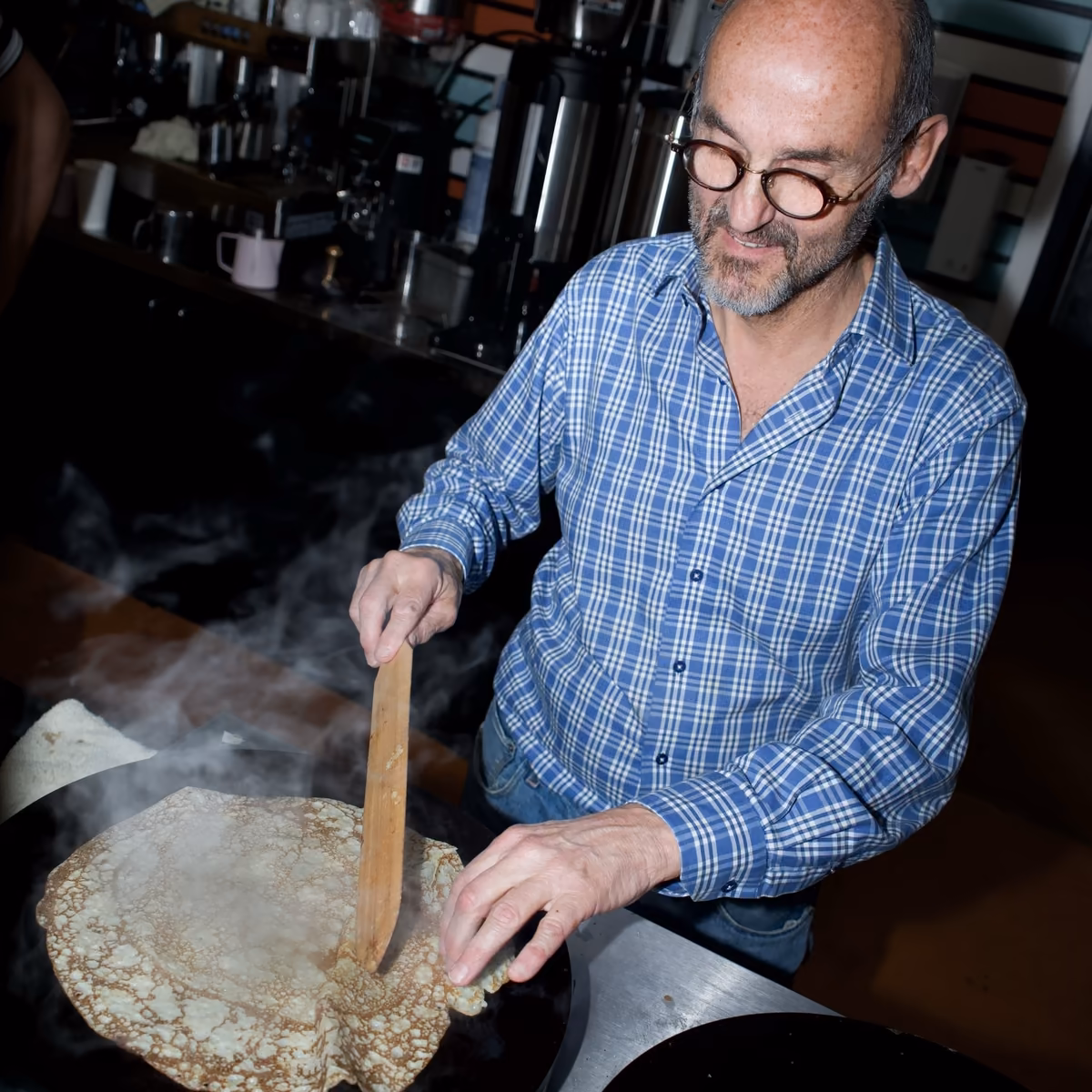 Owner Jerome Gombert lifting a crêpe from the griddle with a wooden spatula